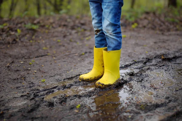 Zlomyslné Předškolní Dítě Žlutých Gumových Holínkách Skákající Velké Kaluži Bláta — Stock fotografie