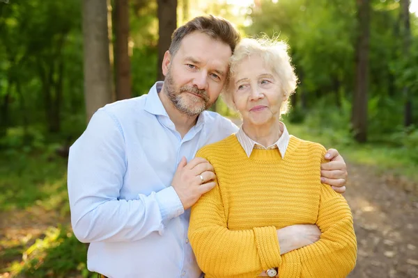 Loving Adult Son Tenderly Embracing His Joyful Elderly Mother Walking — Stock Photo, Image