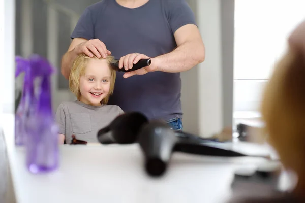 在检疫期间 学龄前男孩在家理发 父亲用剪子剪短他儿子的刘海 镜中的倒影 理发店关门时父母给孩子剪头发 — 图库照片