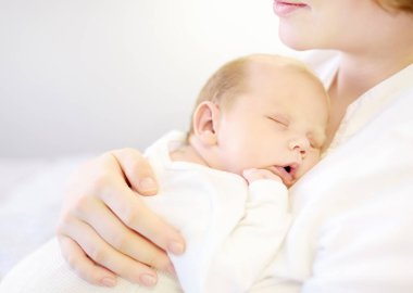 Anne yeni doğmuş bebeğini kucağında tutuyor. Genç bir anne olarak ilk gününün tadını çıkaran bir kadın ve tatlı bir çocuğu var. Anneliğin mutluluğu. Anneler Günü.