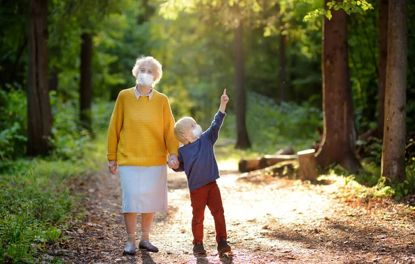 おばあちゃんとお孫さんが夏の公園を一緒に歩いている おばあちゃんと孫 二代にわたる家庭 ウイルスのロックダウン命令を解除 社会的距離 — ストック写真
