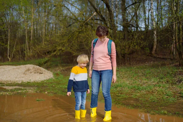 장난기가 취학전 어린이 와성인 커다란 흙탕물 속에서 도약하는 노란색 고무장화를 — 스톡 사진