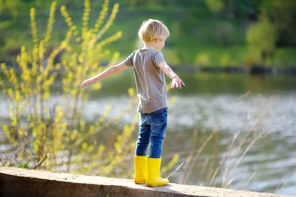 Sarı Çizme Giyen Anaokulu Çocuğu Yağmurdan Sonra Nehrin Kenarında Yürüyor — Stok fotoğraf