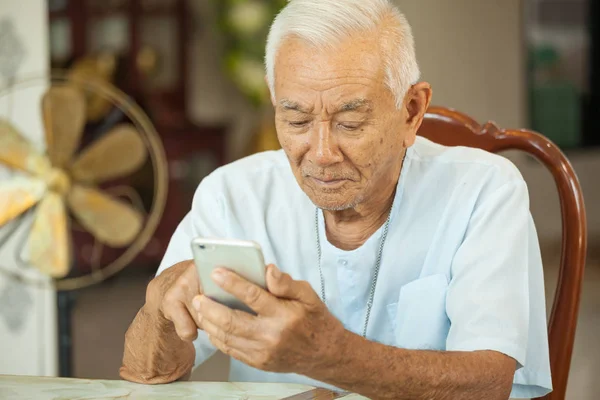 Felice asiatico anziano uomo utilizzando il cellulare a casa — Foto Stock