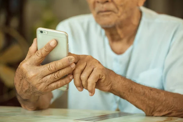 Boldog ázsiai magas rangú ember, otthon a mobiltelefon használata — Stock Fotó