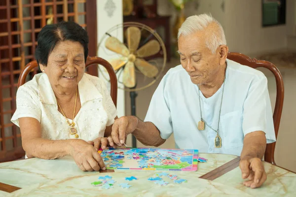 Asiatisches Paar Senior spielt zu Hause mit einem Puzzle — Stockfoto