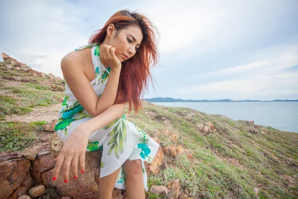 Jonge Aziatische vrouw zitten op een klif op de achtergrond van de mounta — Stockfoto