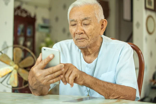Lycklig asiatiska senior man använder mobiltelefonen hemma — Stockfoto