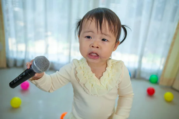 Glad liten asiatisk tjej med mikrofon i hemmet — Stockfoto