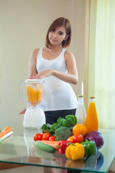 Hermosa mujer asiática joven haciendo batido de frutas en licuadora — Foto de Stock