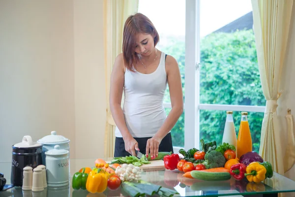 Feliz mujer asiática cocinar verduras ensalada verde en la cocina —  Fotos de Stock