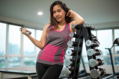 Dambıllarla egzersiz yapan kadın.