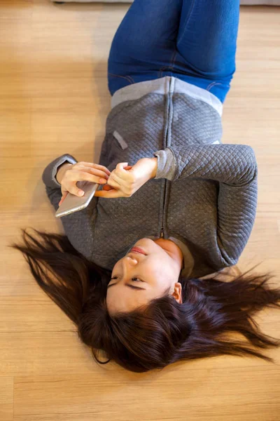 Happy asian young woman lying using smart phone — Stock Photo, Image