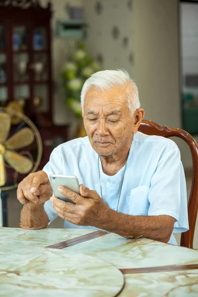 Homem sênior usando o telefone celular em casa — Fotografia de Stock