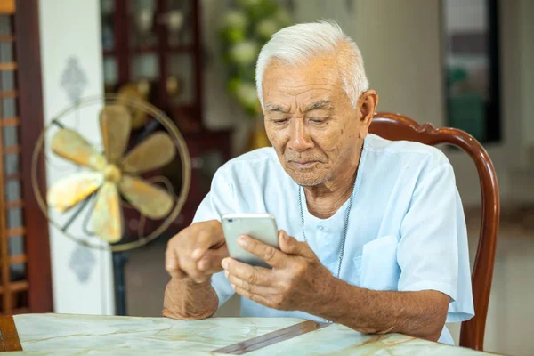 Hombre mayor usando el teléfono móvil en casa — Foto de Stock
