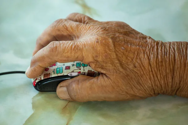Mão de uma velha segurando um mouse de computador . — Fotografia de Stock