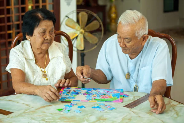 Couple senior playing with a jigsaw puzzle at home — Stock Photo, Image