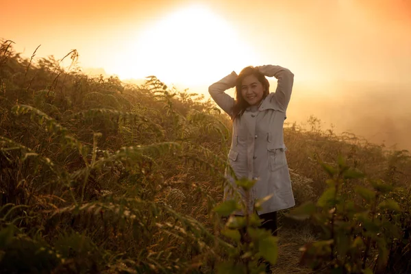 Jovem mulher em um penhasco com vista para as montanhas — Fotografia de Stock