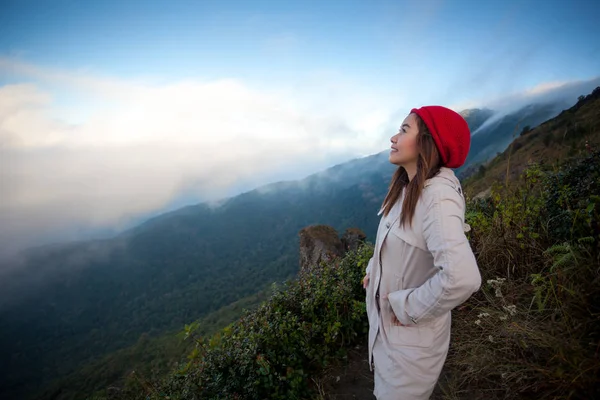 Jovem mulher em um penhasco com vista para as montanhas — Fotografia de Stock