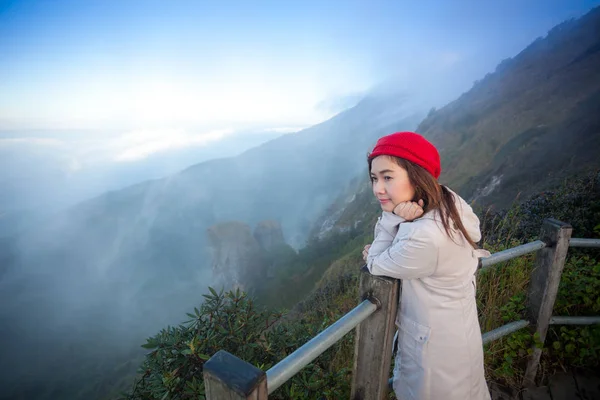 Jovem mulher em um penhasco com vista para as montanhas — Fotografia de Stock