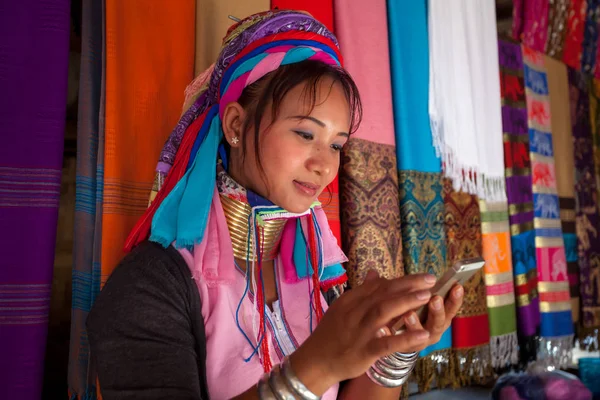 Mujer vistiendo el tradicional con el teléfono móvil en un tejido en Imágenes de stock libres de derechos