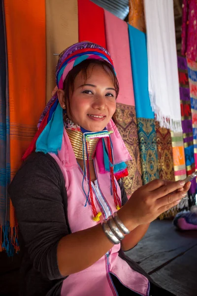 Mujer vistiendo el tradicional con el teléfono móvil en un tejido en Imágenes de stock libres de derechos