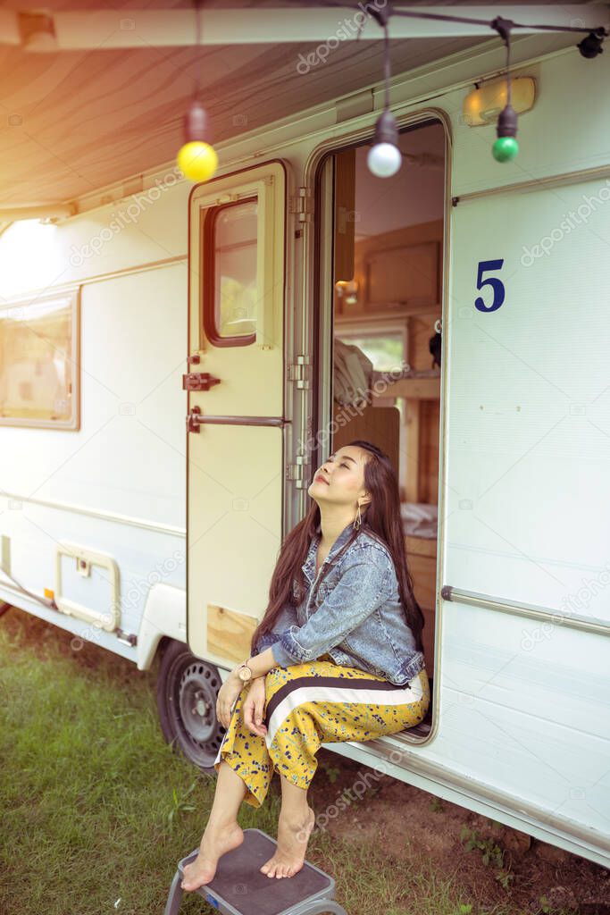 Beautiful young asian woman in a camper van on a summer day