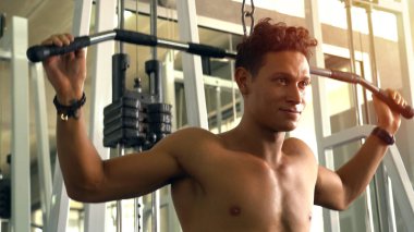 Spor salonunda egzersiz yapan kaslı bir adam.