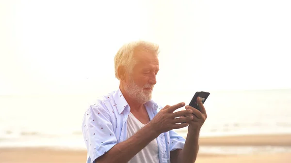 Sorridente Uomo Anziano Messaggio Testo Attraverso Telefono Cellulare Spiaggia — Foto Stock