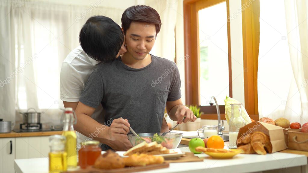 Asian gay couple homosexual cooking together in the kitchen