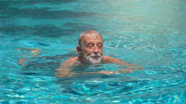 Senior man swimming in an outdoor swimming pool
