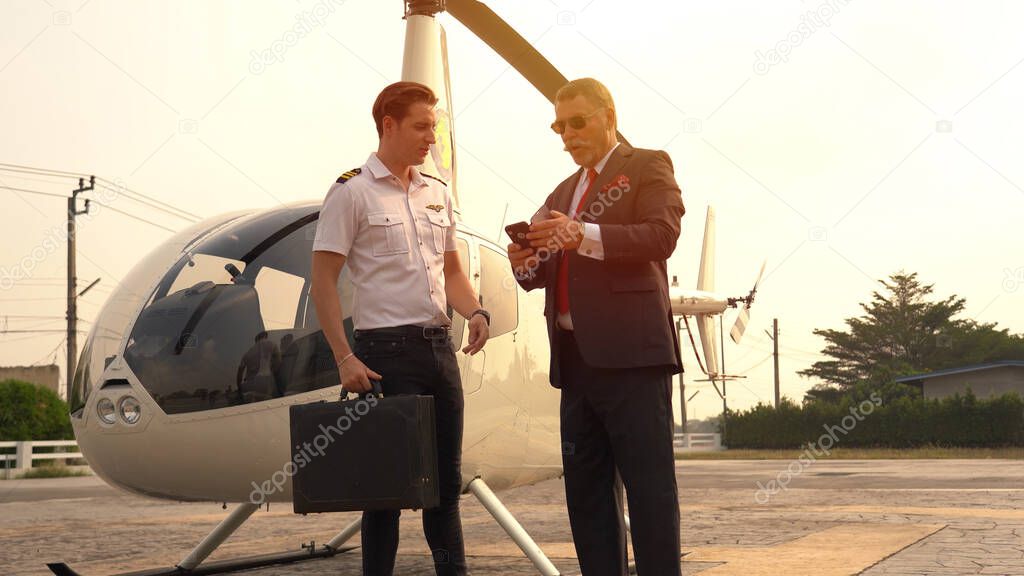 Business man and pilot talking near small private helicopter on a landing point