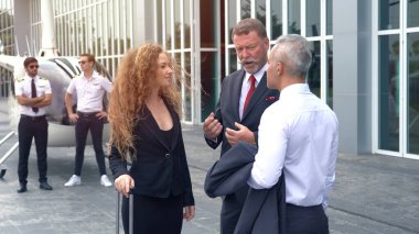 İş adamı ve pilot iniş noktasında küçük özel bir helikopterin yanında konuşuyorlar.