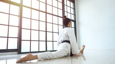 Genç Asyalı kadın ısınma sırasında bacağını dümdüz uzatıyor.