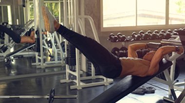 Kas egzersizi yapan adam spor salonunda oturur.