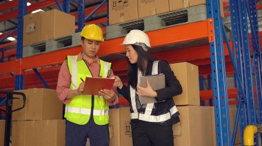 Dağıtım deposunda çalışırken sevkiyatı kontrol eden depo çalışanları.