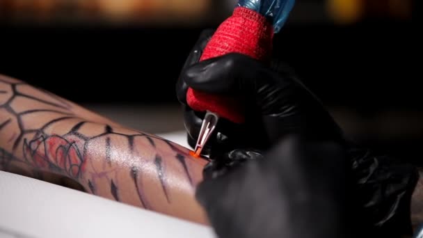 Professzionális tetováló művész teszi a színátmenet tetoválás egy fiatal lány kezét. Közelről