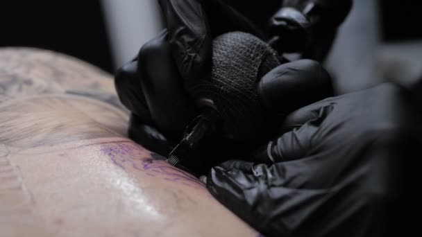 Közelkép tetováló művész bemutatja a folyamat szerzés fekete tetoválás festék hátán egy ügyfél