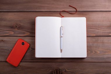 Kırmızı defter ve koyu ahşap arka plan bir smartphone.
