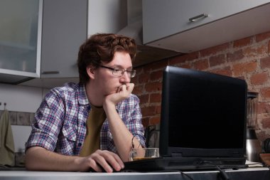 Bir dizüstü bilgisayar ve sorunun çözümü hakkında düşünüyor oturan genç adam