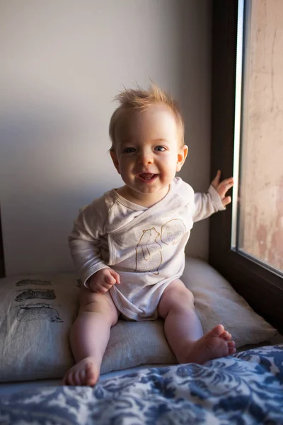 Portret małego chłopca, który siedzi w oknie i uśmiecha się. koncepcja emocje. — Zdjęcie stockowe