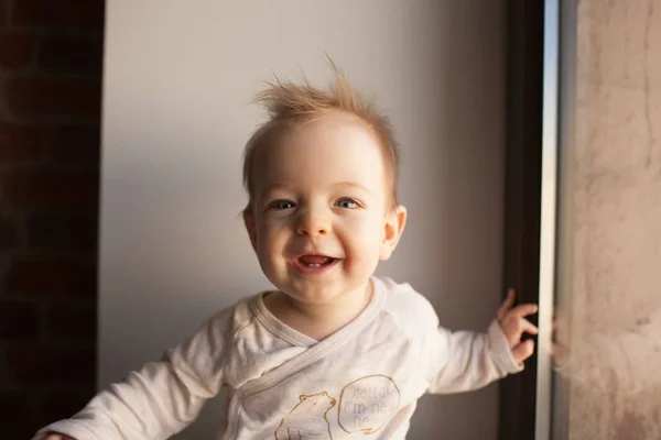 Retrato de un niño pequeño que está sentado en la ventana y sonriendo. concepto de emociones . — Foto de Stock