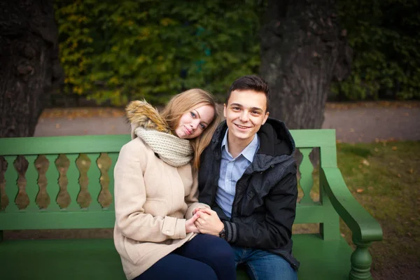Ung pojke och flicka kramar och Kyssar, sitter på bänken — Stockfoto