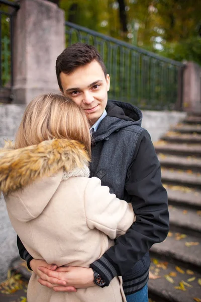 Una chica joven y un chico están caminando por el parque, abrazándose y besándose. humor romántico — Foto de Stock