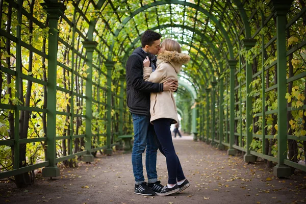 Ung tjej och en kille går genom parken, kramas och kyssas. romantisk stämning — Stockfoto