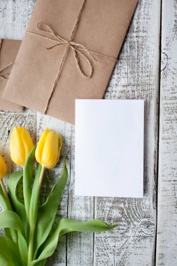 Sarı Lale buketi ve boş tebrik kartı. Ahşap masa üzerinde Üstten Görünüm