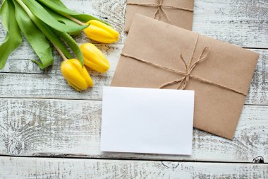 Sarı Lale buketi ve boş tebrik kartı. Ahşap masa üzerinde Üstten Görünüm