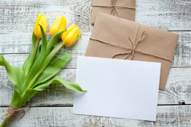 Sarı Lale buketi ve boş tebrik kartı. Ahşap masa üzerinde Üstten Görünüm