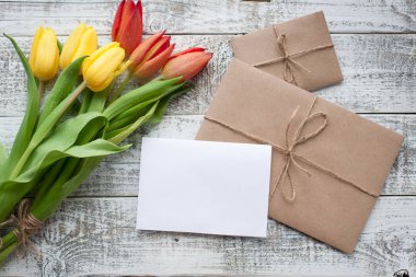 Sarı ve kırmızı lale buketi ve boş tebrik kartı. Ahşap masa üzerinde Üstten Görünüm