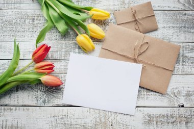 Sarı ve kırmızı lale buketi ve boş tebrik kartı. Ahşap masa üzerinde Üstten Görünüm